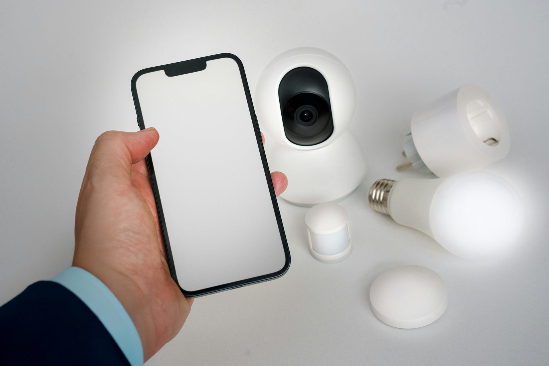 Una persona sosteniendo un teléfono inteligente junto a una cámara.